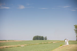 広い美瑛の草原に立つ新郎新婦