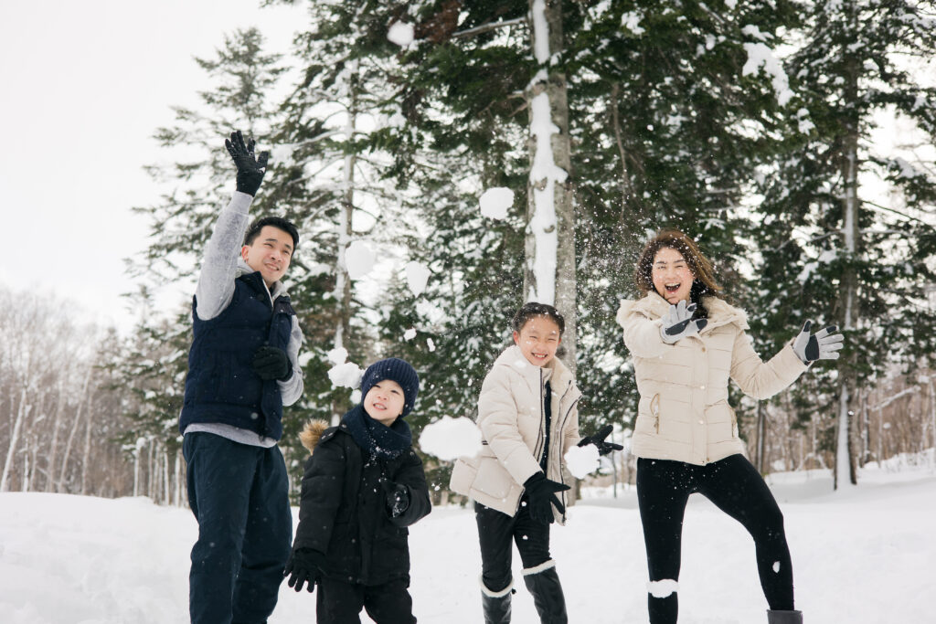 Two children and their parents throwing snow