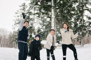 Two children and their parents throwing snow
