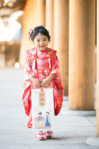 千歳飴を持って立つ七五三の着物を着た女の子