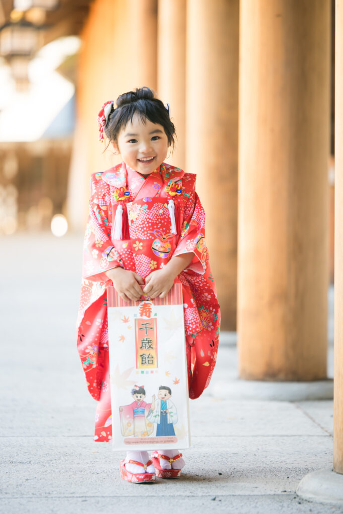 千歳飴を持って立つ七五三の着物を着た女の子