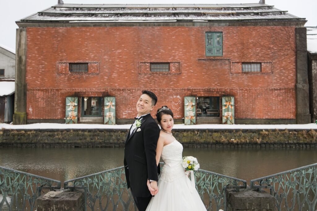 小樽運河沿いで背中合わせに立つ新郎新婦