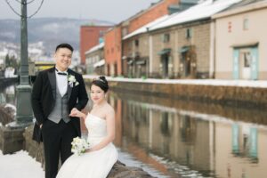小樽運河のブロックに腰掛け正面を向く新郎新婦