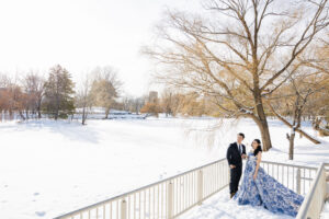 雪で覆われた池のそばに立つ新郎新婦